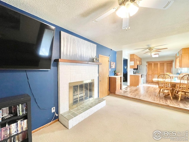 carpeted living room with ceiling fan, a textured ceiling, and a brick fireplace