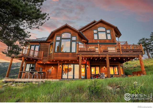 back house at dusk featuring a deck