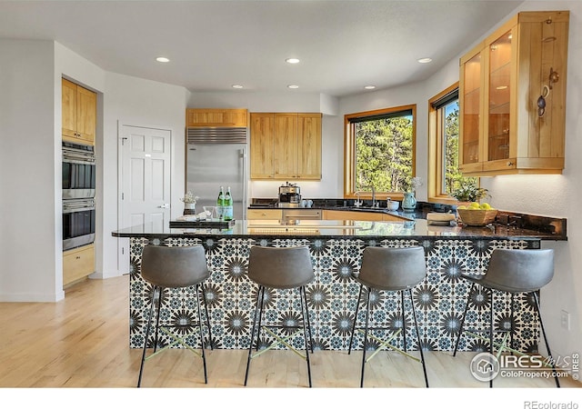 kitchen featuring a breakfast bar area, kitchen peninsula, stainless steel appliances, and light hardwood / wood-style floors