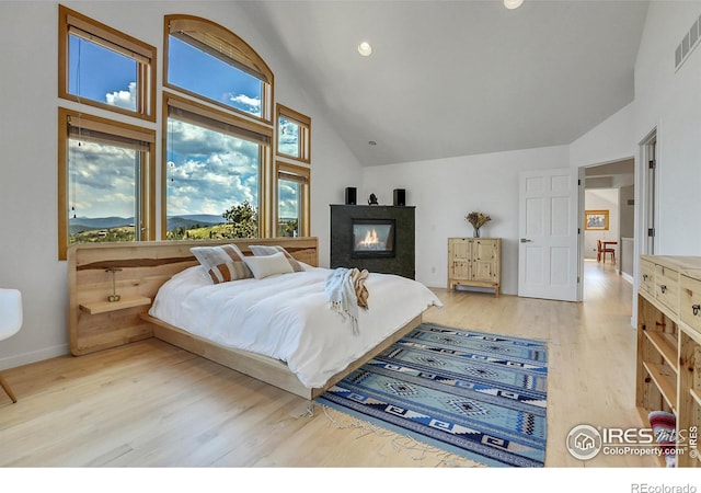 bedroom featuring high vaulted ceiling and light hardwood / wood-style floors