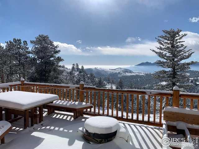 snow covered deck with a mountain view