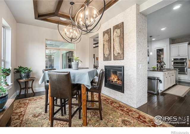 dining area with a notable chandelier, sink, a fireplace, and dark wood-type flooring