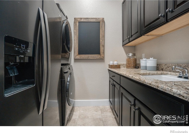 laundry area featuring stacked washer / dryer, sink, and light tile patterned floors