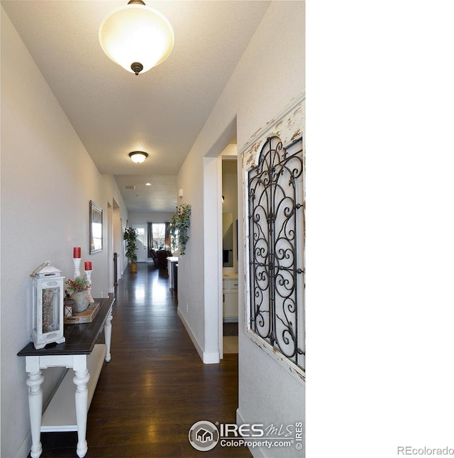 corridor featuring dark wood-style floors and baseboards