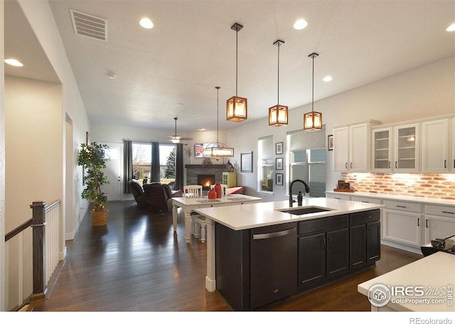 kitchen with stainless steel dishwasher, sink, decorative light fixtures, white cabinetry, and an island with sink