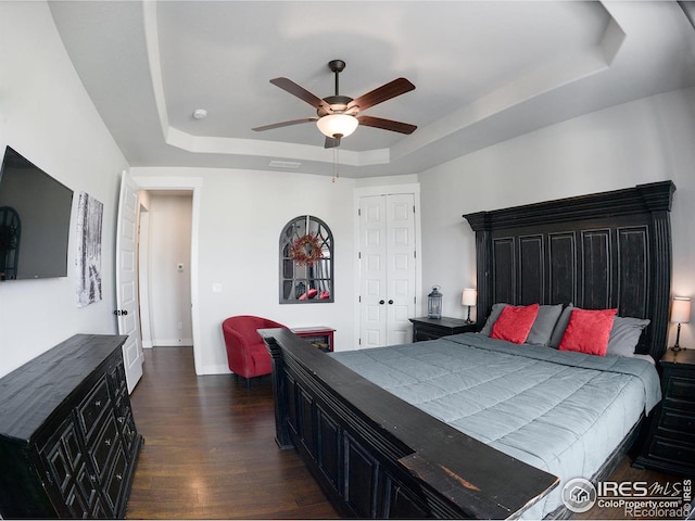 bedroom featuring dark hardwood / wood-style flooring, a raised ceiling, and ceiling fan