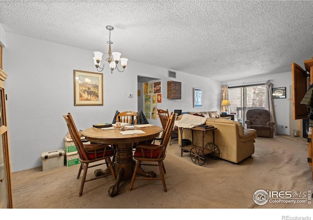 dining room featuring light carpet, a textured ceiling, and a notable chandelier