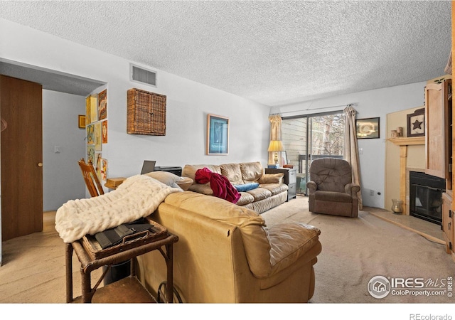 living room with a tile fireplace, a textured ceiling, and light colored carpet