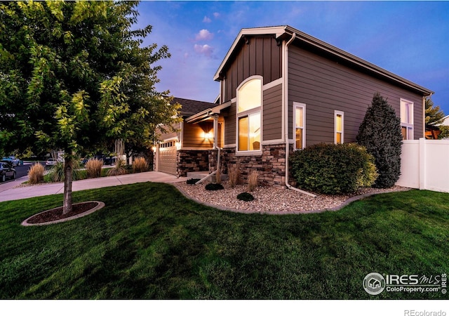 property exterior at dusk featuring a lawn and a garage