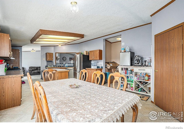 dining space featuring a textured ceiling, light tile patterned floors, and crown molding