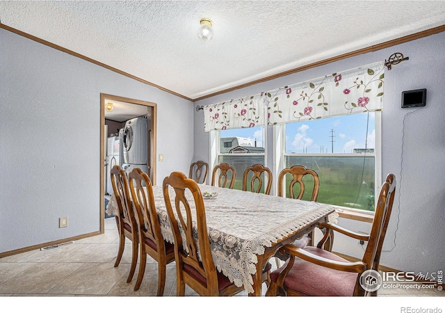 tiled dining space featuring a textured ceiling, stacked washing maching and dryer, and lofted ceiling