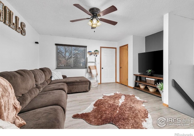 living room with a textured ceiling, light hardwood / wood-style flooring, and ceiling fan