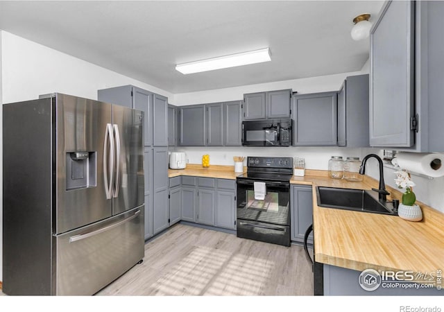 kitchen featuring black appliances, gray cabinetry, light wood-type flooring, and sink