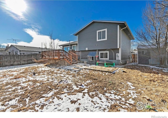 snow covered back of property with a deck