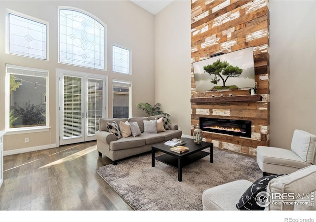 living room with a towering ceiling, french doors, a fireplace, and dark hardwood / wood-style floors