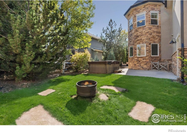 view of yard featuring a hot tub, an outdoor fire pit, and a patio area