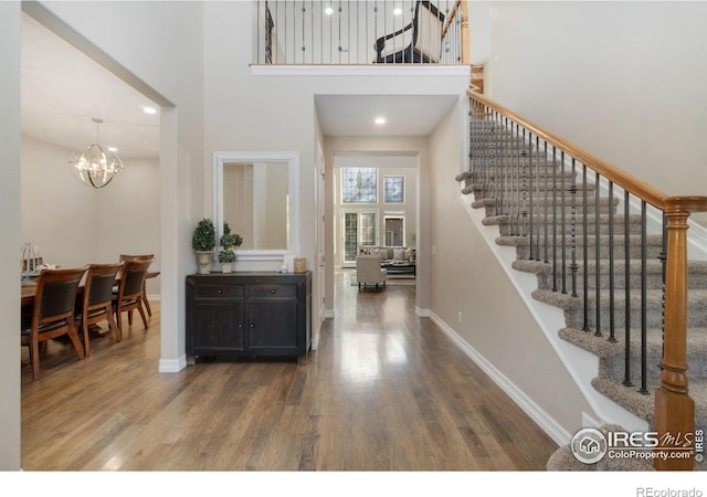 foyer entrance featuring a high ceiling, a chandelier, and wood-type flooring