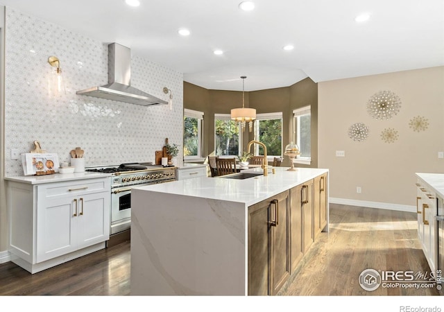 kitchen with sink, range with gas cooktop, a center island with sink, and wall chimney exhaust hood