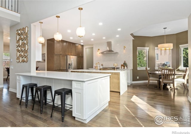 kitchen with decorative light fixtures, a large island, backsplash, and wall chimney exhaust hood