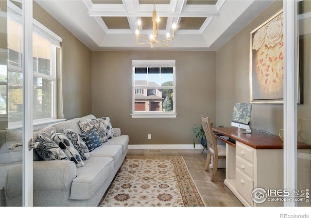 office space featuring a healthy amount of sunlight, a notable chandelier, coffered ceiling, and crown molding