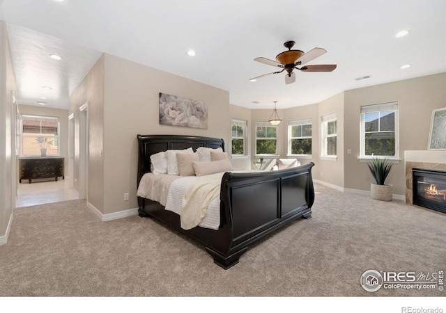 bedroom featuring ceiling fan, multiple windows, and light carpet