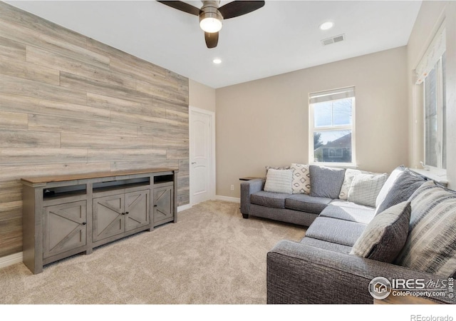 carpeted living room featuring ceiling fan and wooden walls