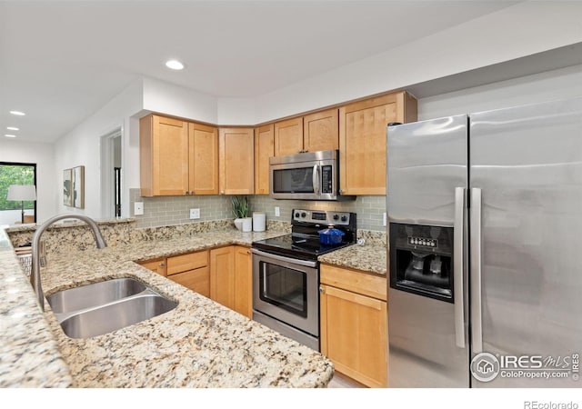 kitchen featuring appliances with stainless steel finishes, sink, light stone counters, and light brown cabinetry