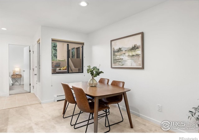 dining area featuring a baseboard heating unit and light carpet