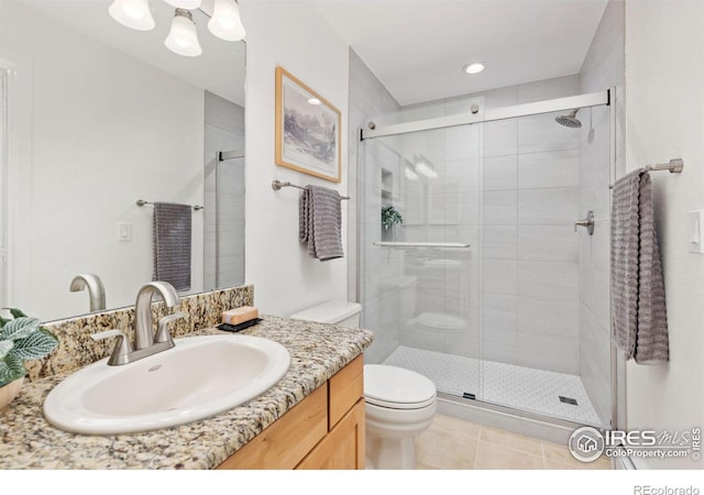 bathroom featuring vanity, a shower with shower door, tile patterned floors, and toilet