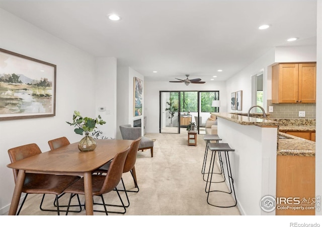 dining space featuring ceiling fan and light carpet