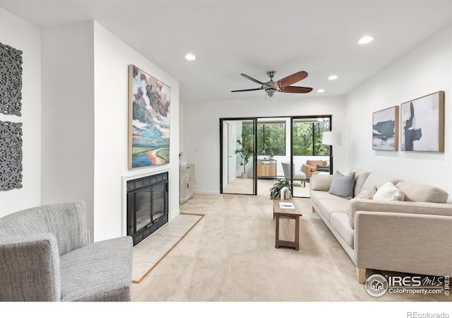 carpeted living room with a tile fireplace and ceiling fan