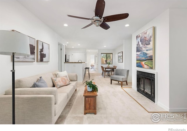 carpeted living room with a tiled fireplace and ceiling fan