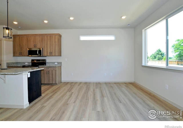 kitchen with light wood-type flooring, stainless steel appliances, sink, pendant lighting, and a breakfast bar area