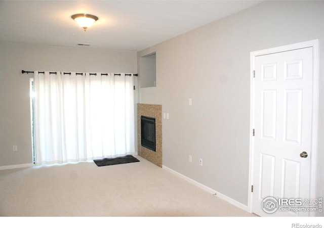 spare room featuring carpet floors and a tile fireplace