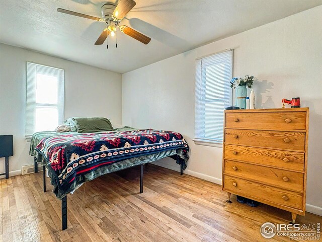 bedroom with ceiling fan, a textured ceiling, and light hardwood / wood-style flooring