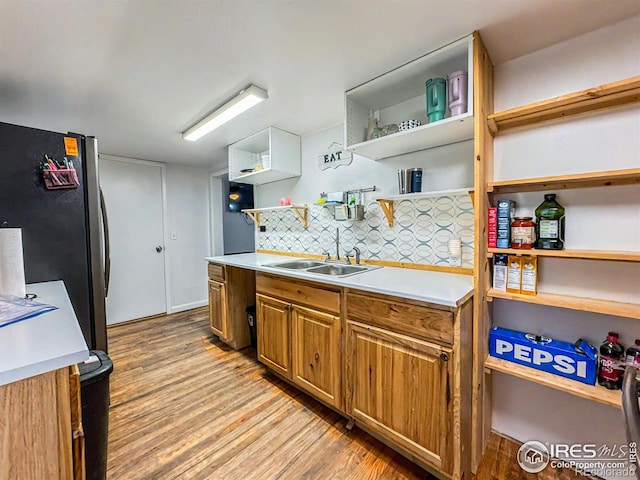 kitchen featuring backsplash, stainless steel refrigerator, sink, and light hardwood / wood-style floors