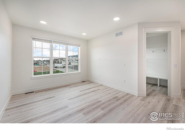 empty room with baseboards, light wood-style flooring, visible vents, and recessed lighting