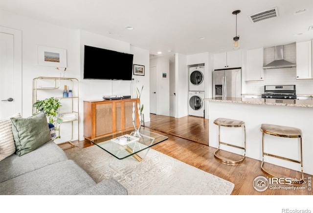 living room with stacked washer / dryer and light hardwood / wood-style flooring