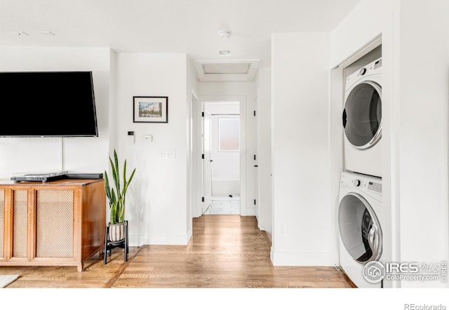 clothes washing area featuring stacked washer / dryer and light hardwood / wood-style floors