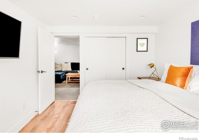 bedroom with light hardwood / wood-style floors and a closet