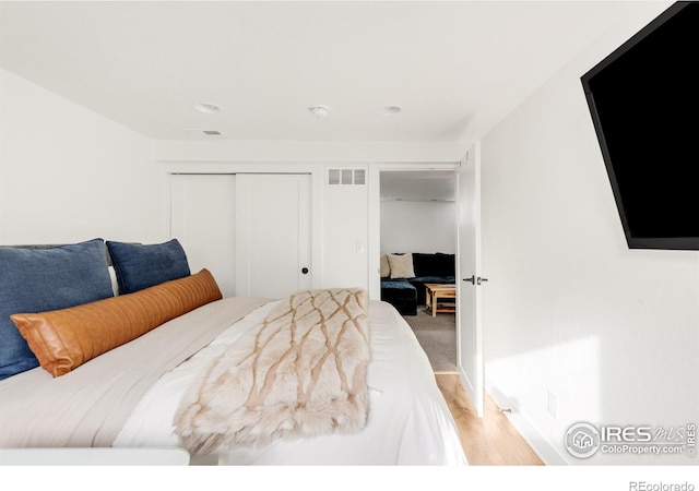 bedroom with light hardwood / wood-style floors and a closet