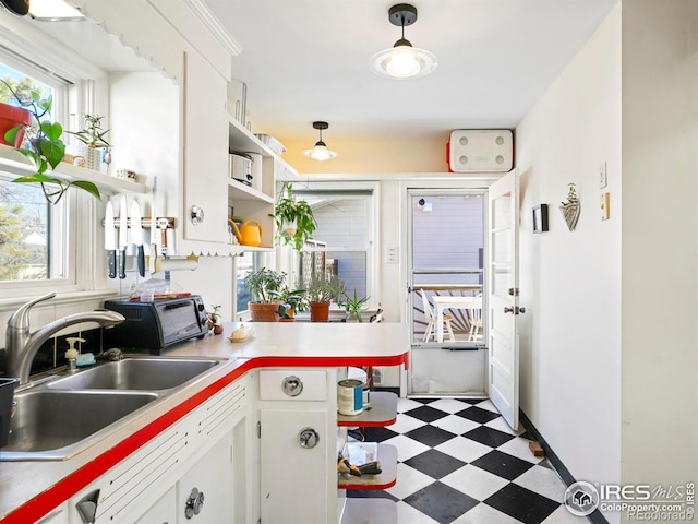 kitchen featuring sink, white cabinets, and pendant lighting