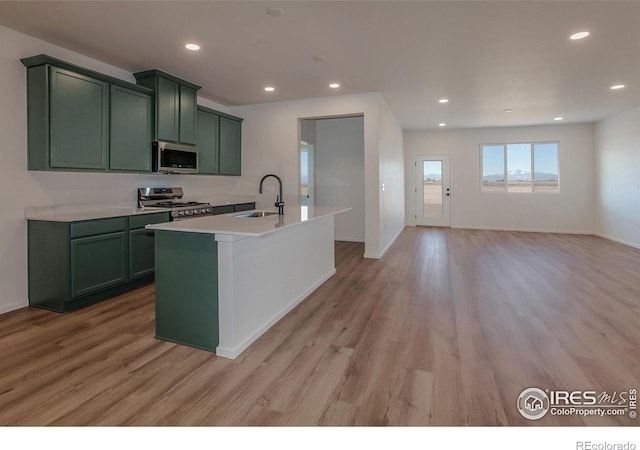 kitchen featuring green cabinets, sink, a center island with sink, and appliances with stainless steel finishes