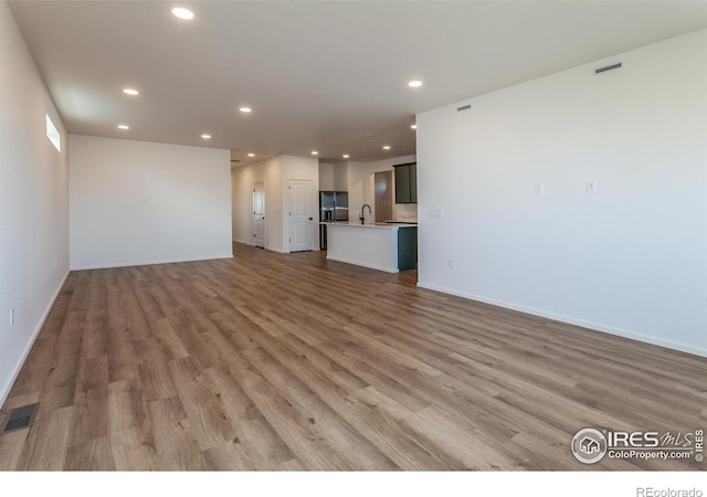 unfurnished living room featuring hardwood / wood-style flooring and sink