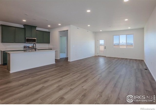 kitchen featuring range, a kitchen island with sink, and light wood-type flooring