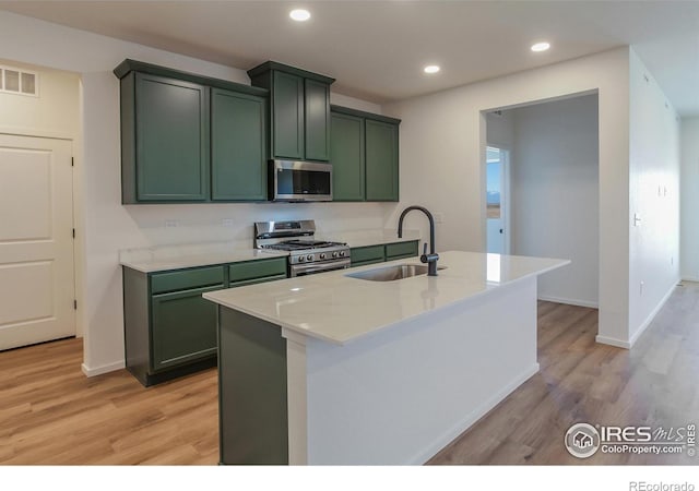 kitchen featuring light stone countertops, stainless steel appliances, green cabinetry, and sink