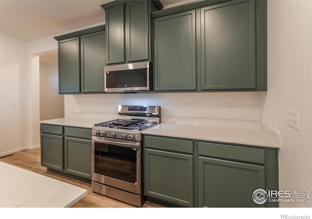 kitchen featuring light hardwood / wood-style floors, green cabinetry, and appliances with stainless steel finishes