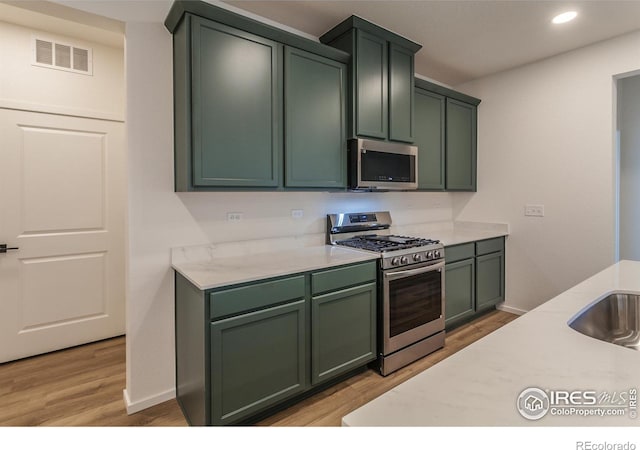 kitchen featuring green cabinets, sink, light wood-type flooring, and stainless steel appliances