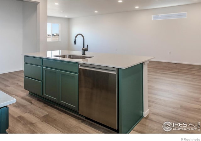 kitchen with green cabinets, a center island with sink, stainless steel dishwasher, and sink