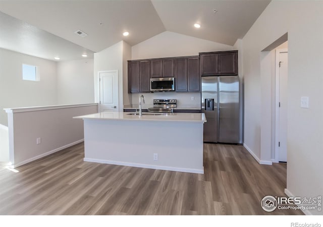 kitchen featuring dark brown cabinets, stainless steel appliances, a kitchen island with sink, sink, and hardwood / wood-style flooring